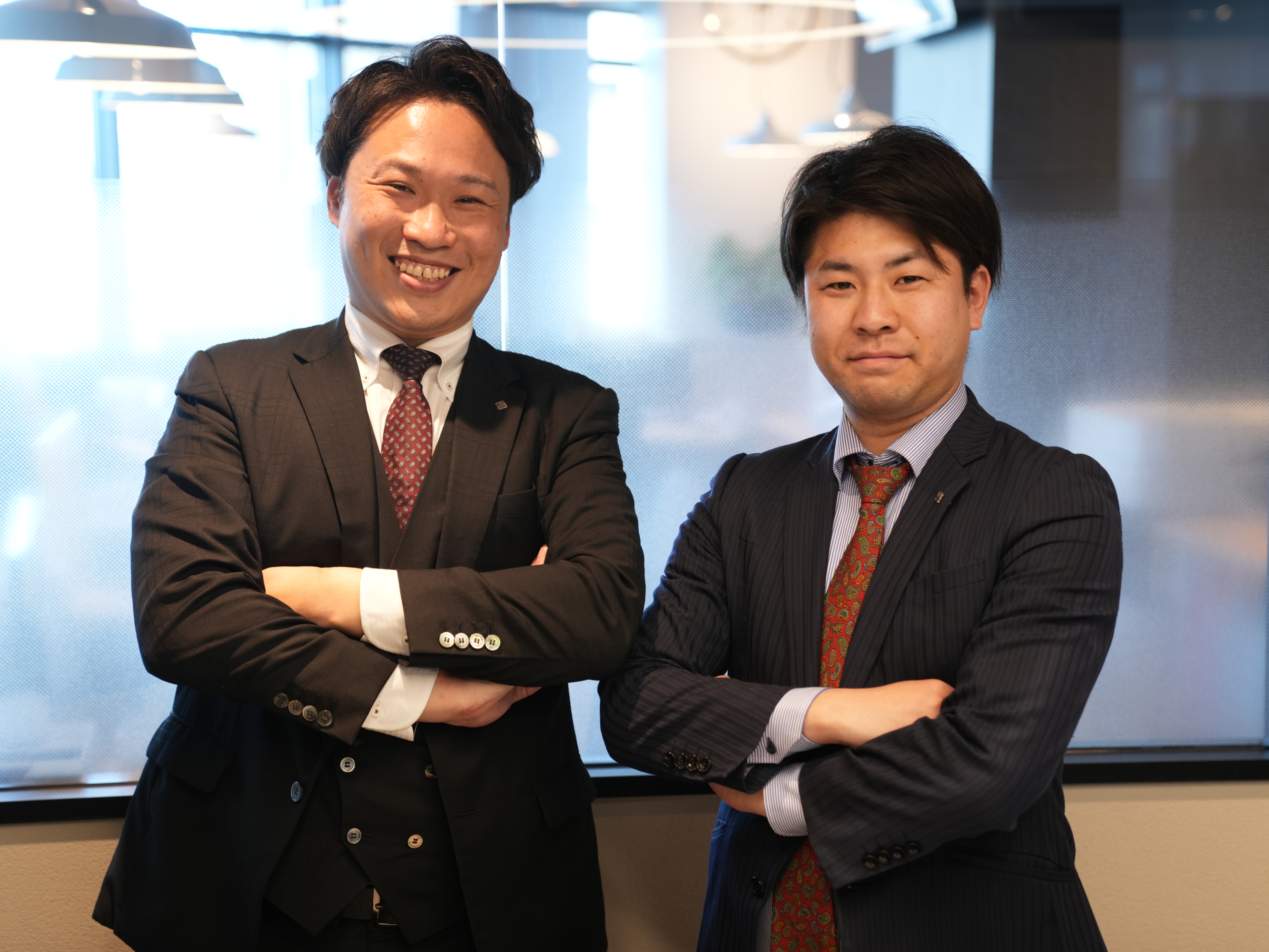 スーツを着ている男性2人が腕を組んでいる様子